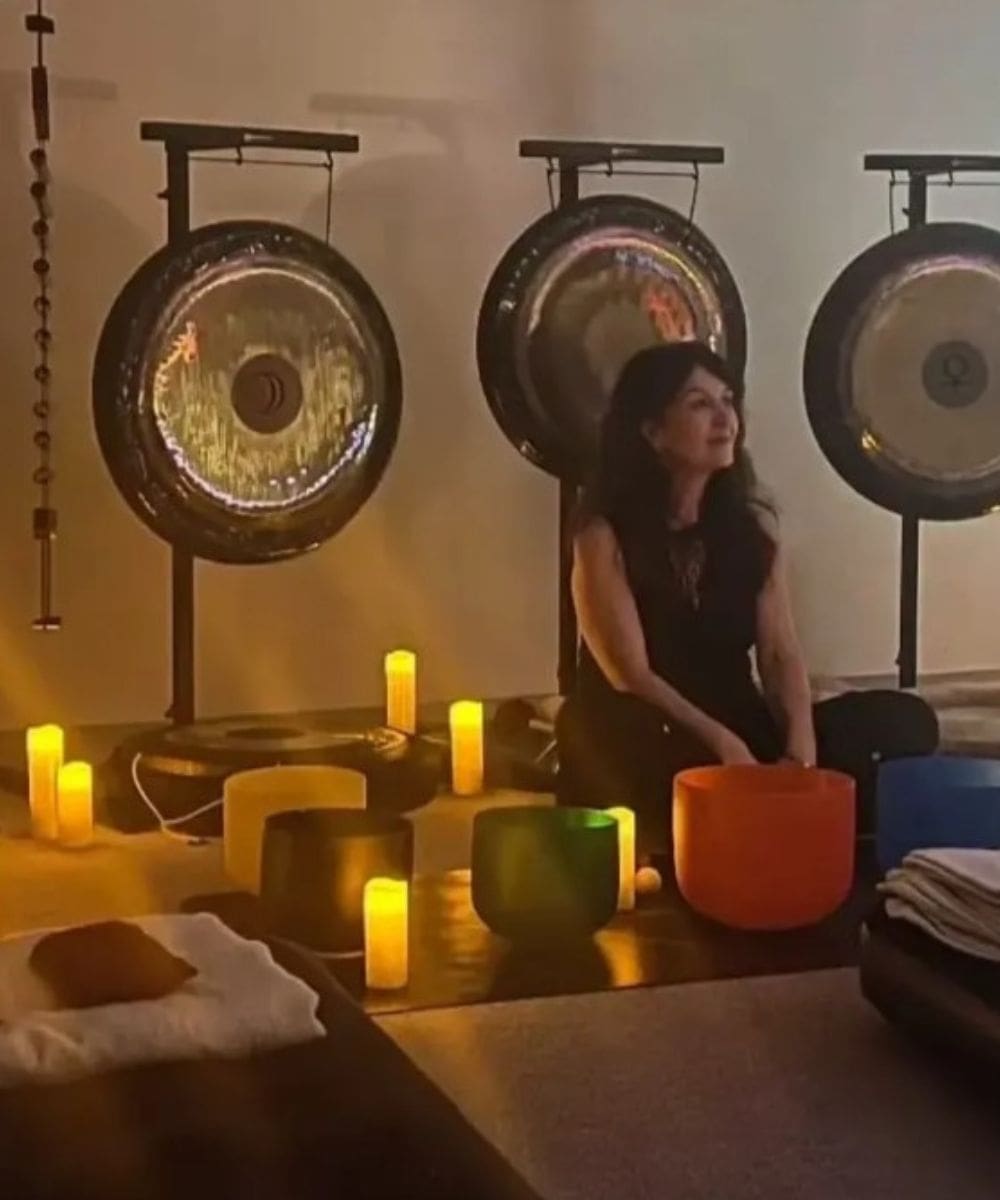 Woman meditating with gongs and candles.